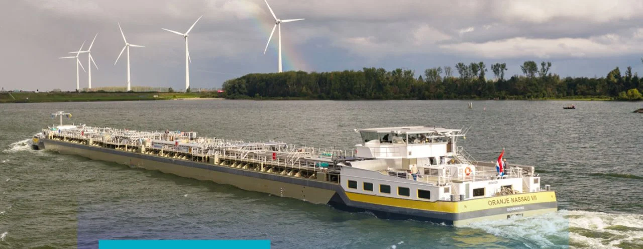 Dronebeeld van de Oranje Nassau VII varend langs windmolens